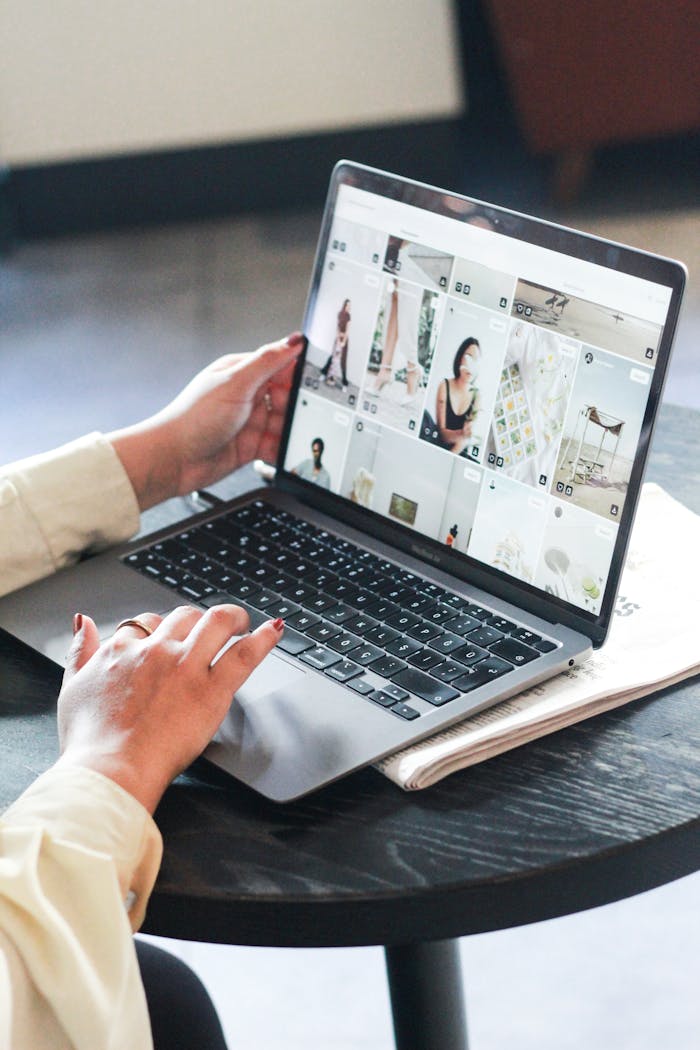 A woman browses a fashion blog on her laptop while working indoors, focused on the screen.