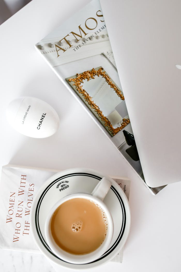 Overhead view of a minimalist workspace featuring coffee, books, and a laptop.