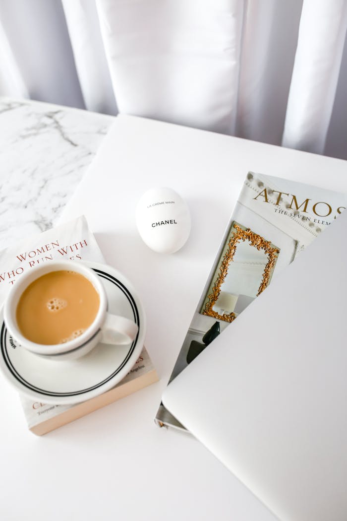 Elegant flat lay featuring coffee, magazine, and decor on a marble surface.